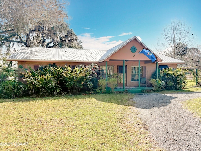 view of front of home featuring metal roof, covered porch, and a front lawn