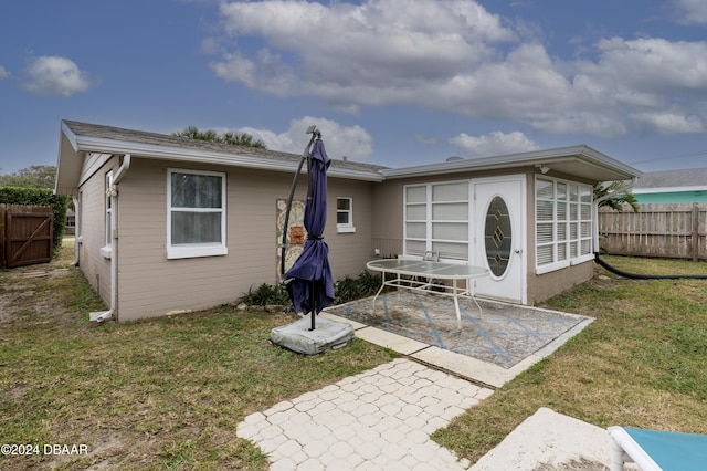 rear view of house featuring a lawn and a patio