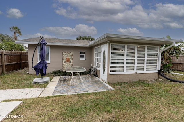 rear view of property featuring a lawn and a patio