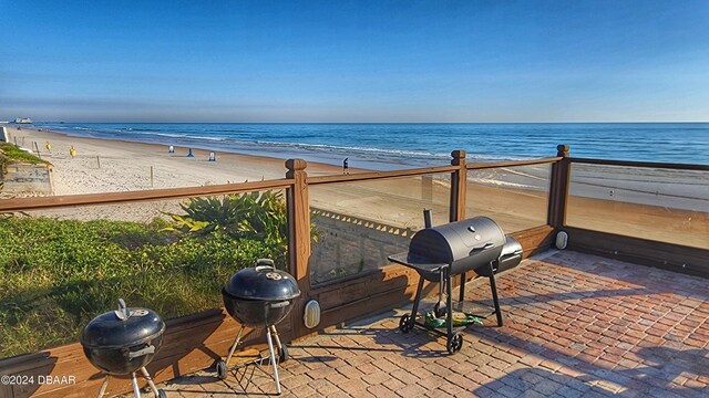 view of patio / terrace featuring a grill, a water view, and a beach view