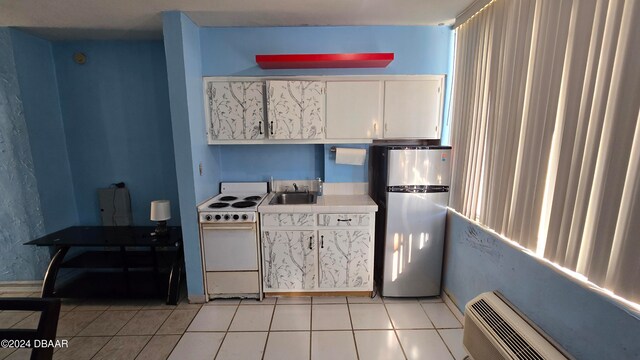 kitchen with white cabinetry, sink, white range, stainless steel fridge, and light tile patterned floors