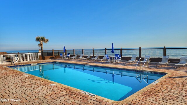 view of pool featuring a water view and a patio