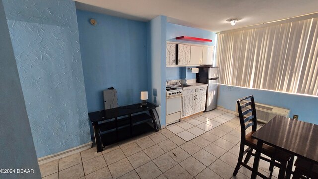 kitchen featuring white cabinets, white range, sink, light tile patterned floors, and stainless steel refrigerator