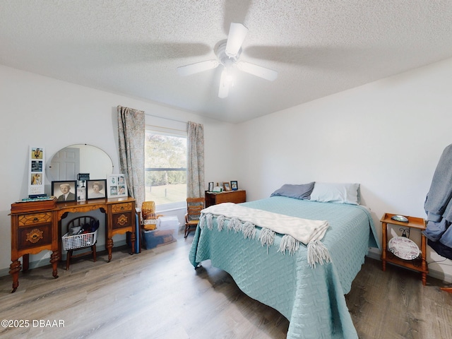 bedroom with a textured ceiling, ceiling fan, and hardwood / wood-style floors