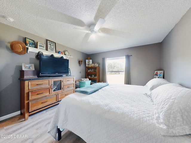 bedroom featuring light wood-type flooring, ceiling fan, and a textured ceiling