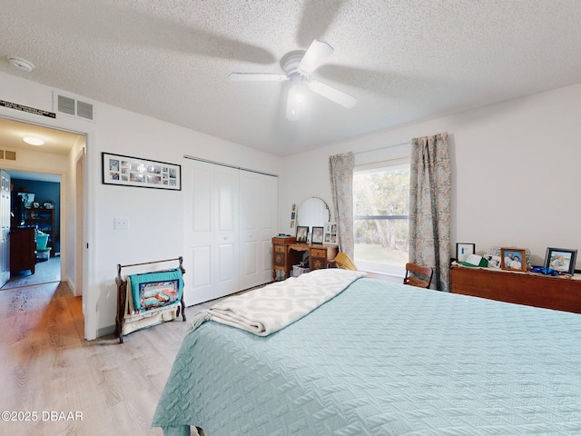 bedroom featuring ceiling fan, a textured ceiling, a closet, and light wood-type flooring