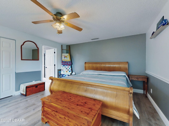 bedroom with a textured ceiling, ceiling fan, and hardwood / wood-style flooring