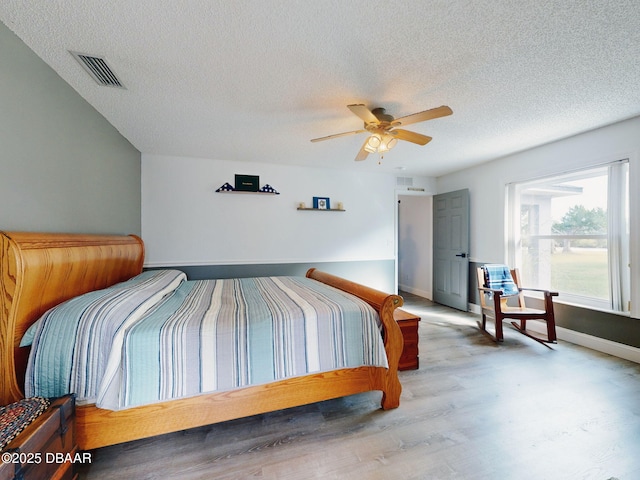 bedroom with ceiling fan, a textured ceiling, and hardwood / wood-style floors