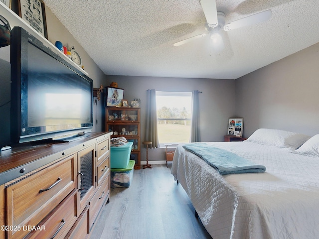 bedroom with a textured ceiling, ceiling fan, and light hardwood / wood-style flooring