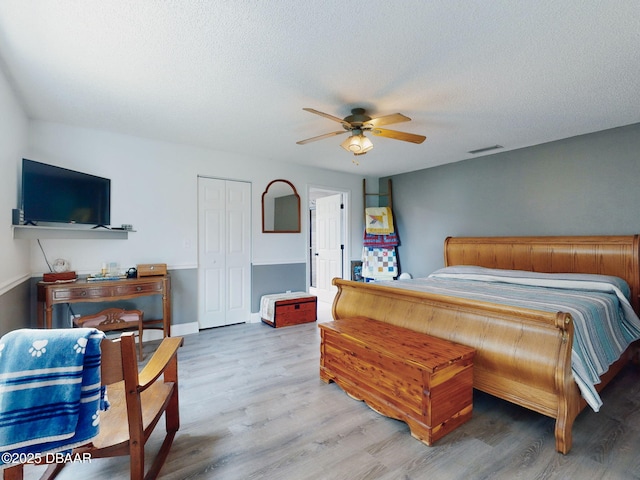 bedroom featuring ceiling fan, hardwood / wood-style floors, a closet, and a textured ceiling