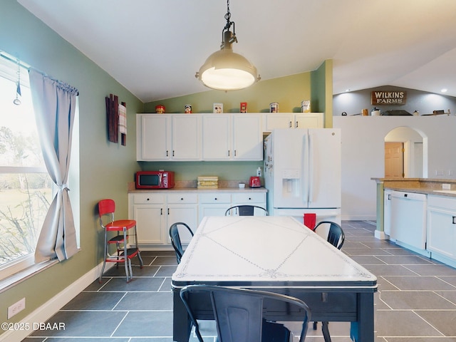 kitchen featuring lofted ceiling, white cabinets, hanging light fixtures, and white appliances