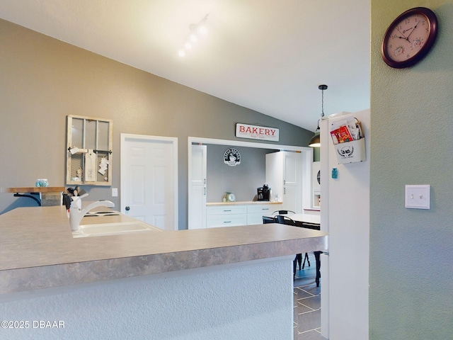 kitchen with vaulted ceiling, tile patterned flooring, hanging light fixtures, and sink