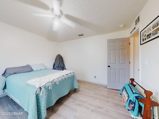 bedroom with ceiling fan, light wood-type flooring, and a textured ceiling