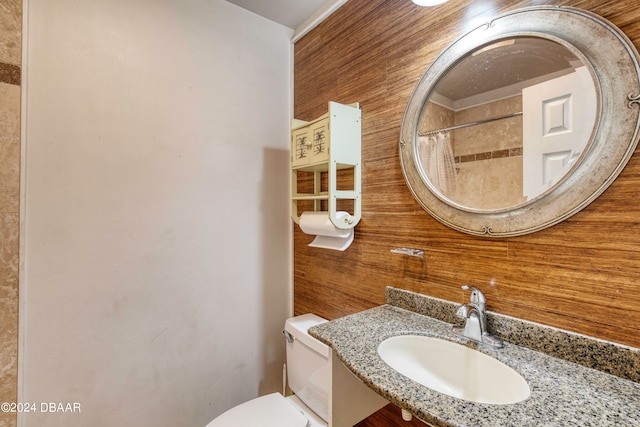 bathroom featuring toilet, wooden walls, sink, and curtained shower