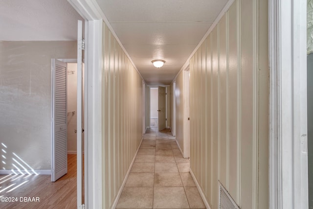 corridor featuring light tile patterned floors and crown molding