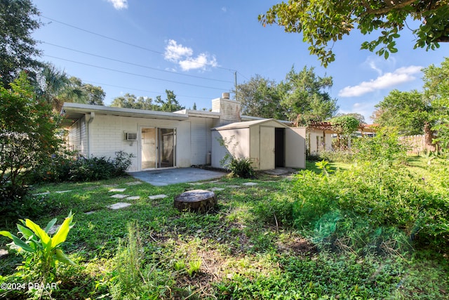 rear view of property featuring a patio and a storage unit