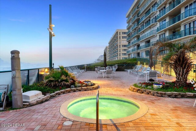 pool at dusk featuring a community hot tub and a patio area