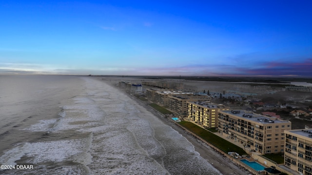 aerial view at dusk featuring a beach view and a water view