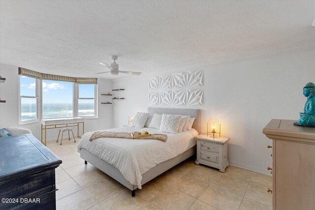 bedroom featuring a water view, a textured ceiling, light tile patterned floors, and ceiling fan