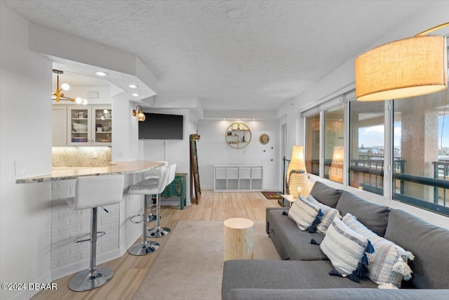 living room with light hardwood / wood-style floors, a textured ceiling, and a notable chandelier