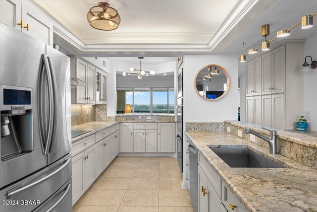 kitchen with stainless steel appliances, sink, tasteful backsplash, a raised ceiling, and pendant lighting