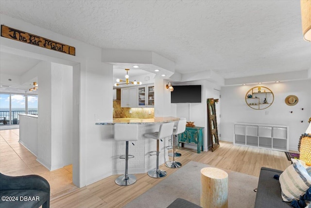 living room featuring an inviting chandelier, a textured ceiling, and light hardwood / wood-style flooring