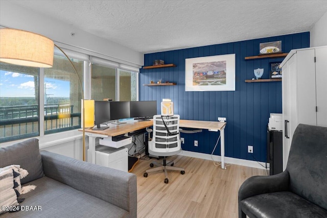 home office featuring wood walls, a textured ceiling, and light wood-type flooring