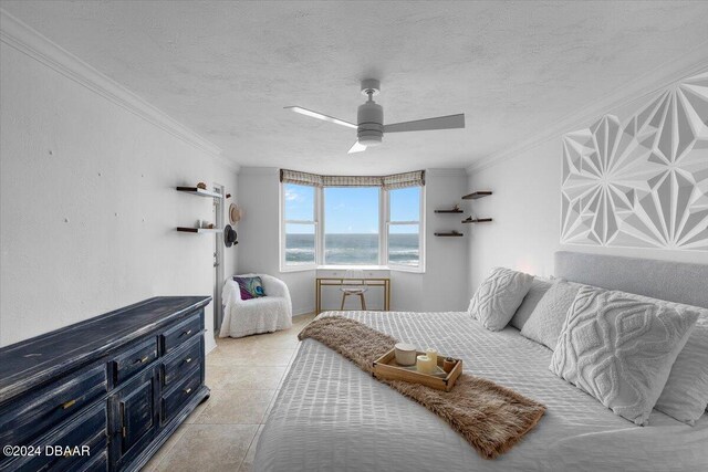 tiled bedroom with ceiling fan, a textured ceiling, a water view, and crown molding