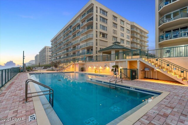 pool at dusk featuring a patio