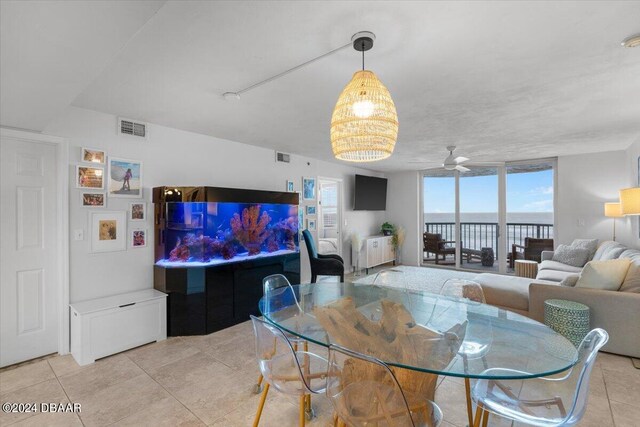 tiled dining area featuring rail lighting, a wall of windows, and ceiling fan with notable chandelier