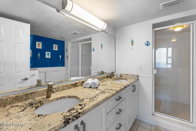 bathroom featuring vanity, a textured ceiling, tile patterned floors, and an enclosed shower