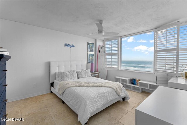 tiled bedroom featuring ceiling fan and a water view