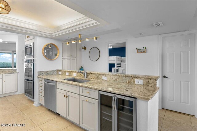 kitchen with wine cooler, white cabinetry, appliances with stainless steel finishes, sink, and a tray ceiling