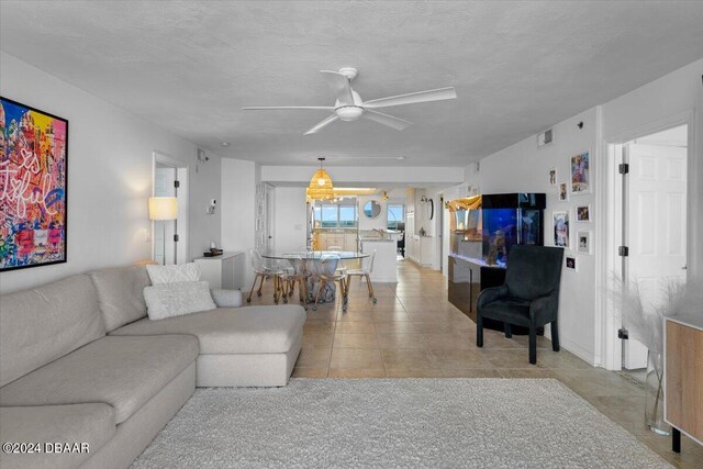 tiled living room with ceiling fan and a textured ceiling