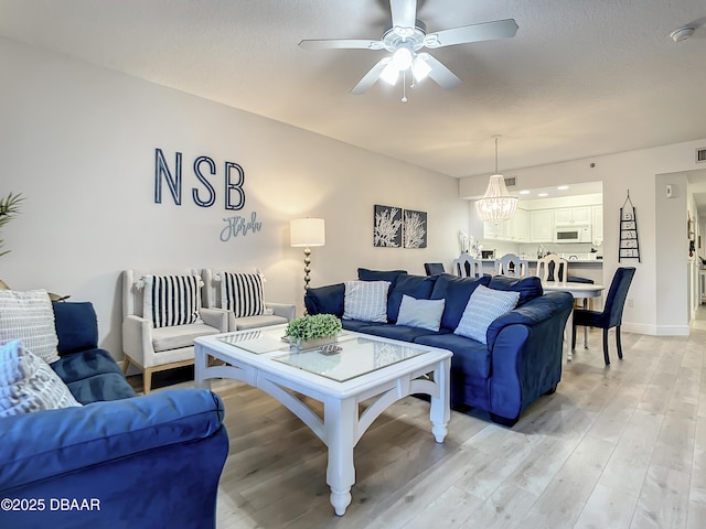 5300 S Atlantic Ave Unit 10-205, New Smyrna Beach, FL 32168 - living area featuring light wood finished floors, visible vents, baseboards, and ceiling fan with notable chandelier