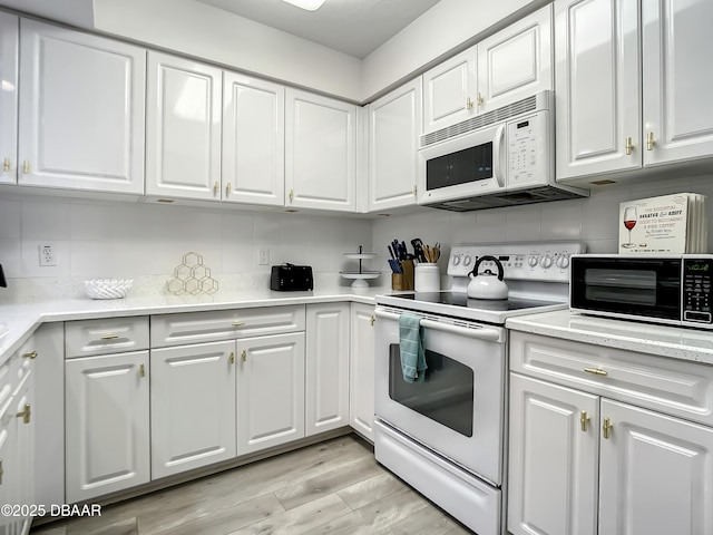 5300 S Atlantic Ave Unit 10-205, New Smyrna Beach, FL 32168 - kitchen featuring light wood-type flooring, white cabinets, white appliances, and backsplash