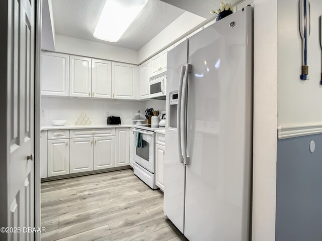 5300 S Atlantic Ave Unit 10-205, New Smyrna Beach, FL 32168 - kitchen featuring light wood finished floors, light countertops, white cabinetry, and white appliances