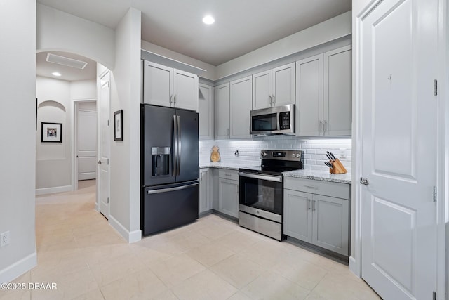 17 Newhaven Ln Unit 17, Ormond Beach, FL 32174 - kitchen featuring stainless steel appliances, gray cabinetry, arched walkways, tasteful backsplash, and light stone counters