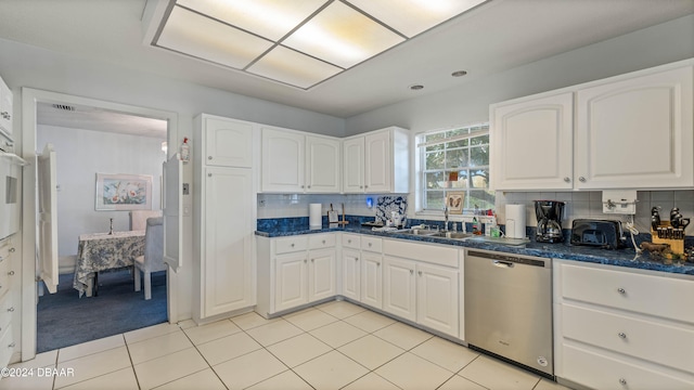 kitchen with backsplash, light tile patterned floors, sink, white cabinets, and stainless steel dishwasher