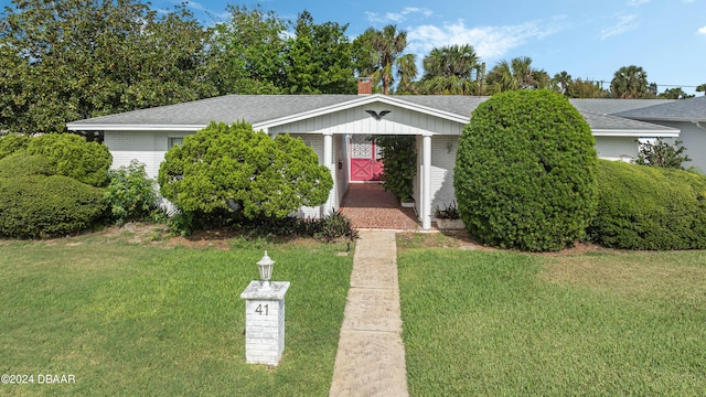 view of front of home with brick siding, a front yard, and a shingled roof