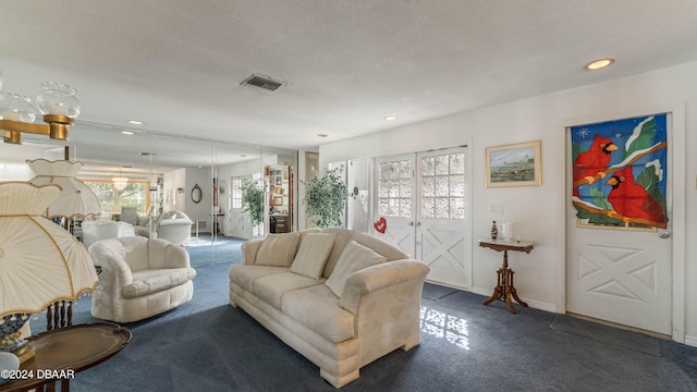 living room with a wealth of natural light, a textured ceiling, and dark carpet