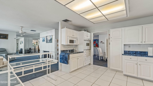 kitchen featuring light tile patterned flooring, backsplash, white cabinets, white appliances, and ceiling fan