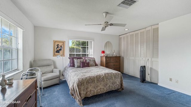 bedroom with a closet, a textured ceiling, dark colored carpet, and ceiling fan