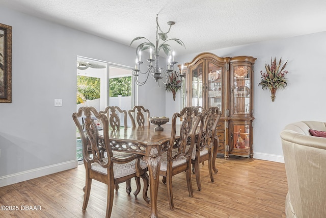 43 Pergola Pl, Ormond Beach, FL 32174 - dining space with baseboards, a notable chandelier, a textured ceiling, and light wood-style flooring