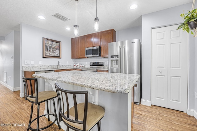43 Pergola Pl, Ormond Beach, FL 32174 - kitchen with visible vents, light wood-type flooring, baseboards, a kitchen bar, and appliances with stainless steel finishes