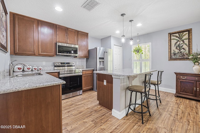 43 Pergola Pl, Ormond Beach, FL 32174 - kitchen with light wood finished floors, stainless steel appliances, a breakfast bar, and a sink