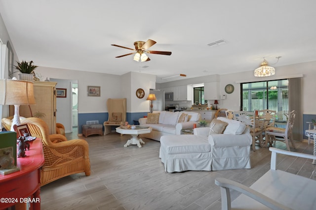 living room featuring light hardwood / wood-style floors and ceiling fan with notable chandelier