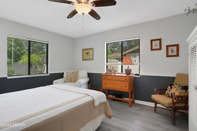 bedroom featuring light hardwood / wood-style floors, ceiling fan, and multiple windows