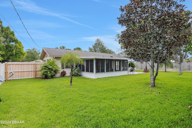 rear view of house with a sunroom and a yard