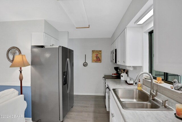 kitchen featuring white cabinetry, stainless steel appliances, wood-type flooring, and sink